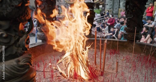 New Taipei City, Taiwan, May 12, 2025: The blazing flames of incense burners in a traditional temple create a dynamic contrast with the crowds of people praying and the magnificent dragon pillar carvi