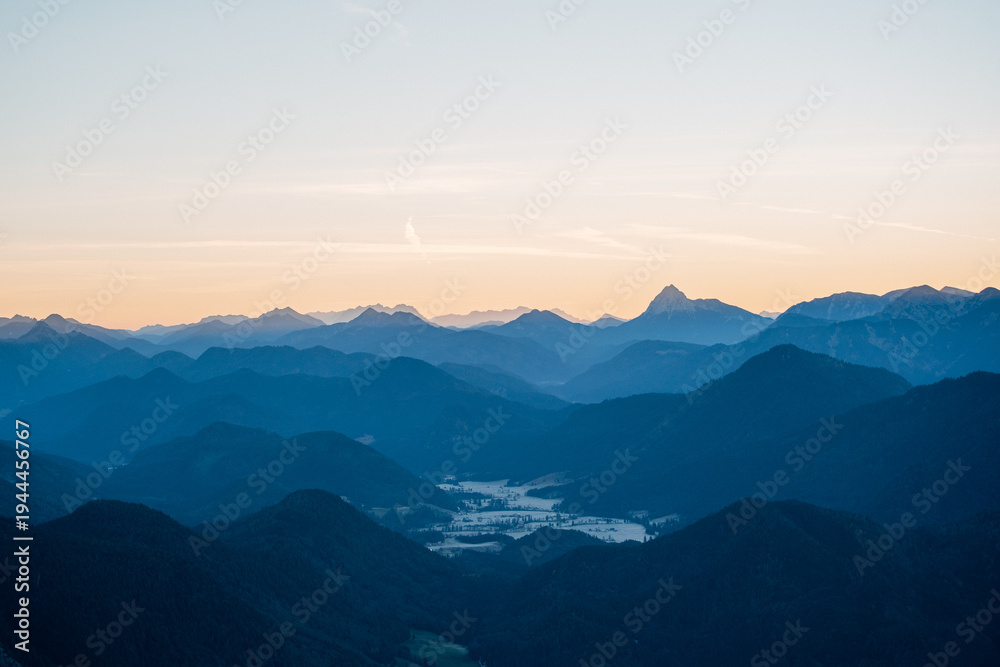 Obraz premium Sun Rays Piercing a Misty Alpine Valley at Golden Hour, Layered Mountain Ranges in Soft Morning Light with Crepuscular Rays