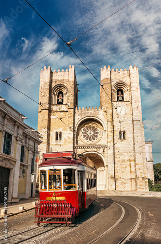 Vintage red tram travels past the iconic Se Cathedral in Lisbon, Portugal, capturing the charm and history. Lisbon, Portugal - 11 June 2025