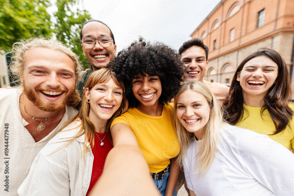 Fototapeta premium Young multiracial group of friends taking selfie outdoors. Happy young people smiling together in an urban European setting. Community and lifestyle concept.