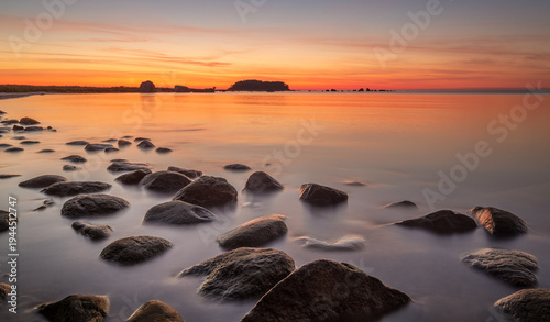 Tableau sur toile Stunning seascape with the colorful sunset sky and calm water at the rocky coastline of the Baltic sea