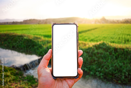 A white phone screen with a background of an agricultural field where farmers utilize technology to improve their livelihoods.