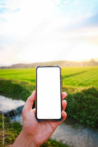 A white phone screen with a background of an agricultural field where farmers utilize technology to improve their livelihoods.