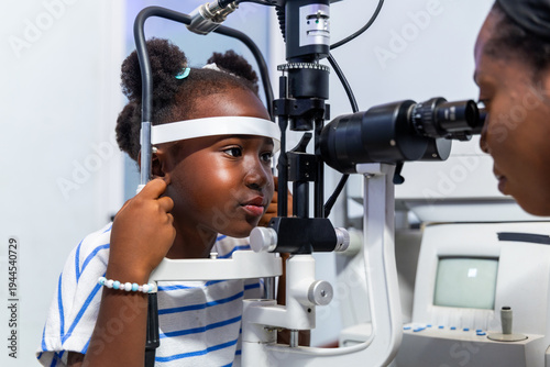 Konstfotografi Young African girl receiving an eye checkup from an optometrist using a slit lam
