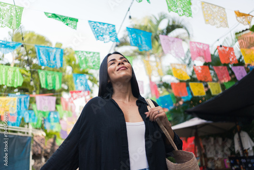 Happy woman surrounded by colorful papel picado decorations in puerto vallarta