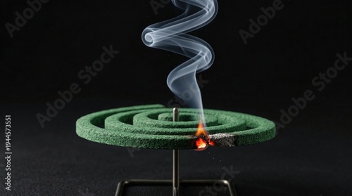 Burning mosquito coil with smoke on dark background. Mosquito repellent concept for outdoor insect protection.