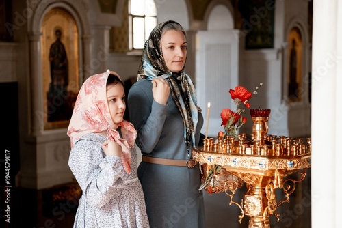 Photos mom and daughter put candles and pray in the Orthodox church, congratulating eac