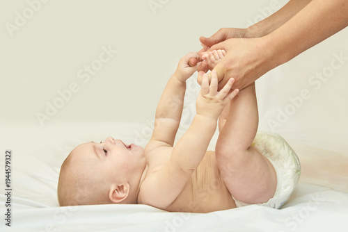 Caucasian Baby Engaging With Adult Hands While Lying On Soft White Blanket.