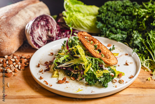 Bild auf Leinwand A simple side salad with fresh bread and almonds on a wooden board with ingredie