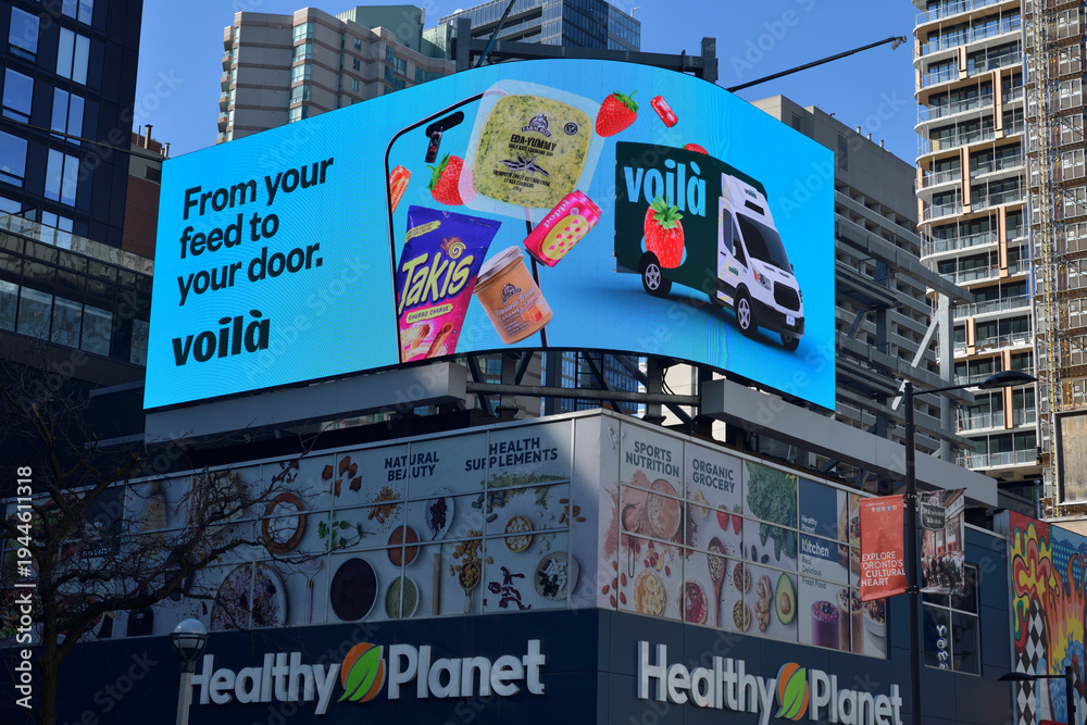 Obraz premium rooftop digital billboard with ad for Voilà, a Canadian online grocery service run by Sobeys, over Healthy Planet - Yonge & Dundas, 322 Yonge St, Toronto