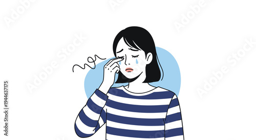 Sad young woman in a striped shirt cries and wipes a tear from her eye with a distressed and emotional facial expression.