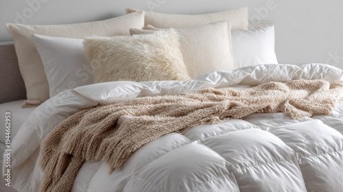 Fluffy white down comforter on bed with beige throw blanket, pillows. Soft, cosy bedding creates tranquil, dreamy atmosphere for ultimate relaxation, sleep
