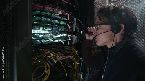 Medium close up shot of network engineer using handheld flashlight to inspect cables and ports inside server rack in modern data center during infrastructure maintenance