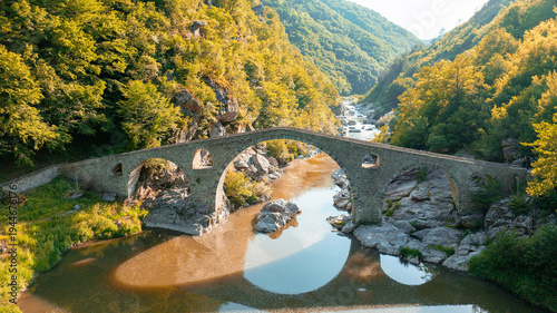 Devils Bridge aerial view Rhodope mountains Bulgaria summer landscape. Ancient stone architecture Arda river water landmark. Drone shot historic bridge Balkan mountains travel photography scenery view