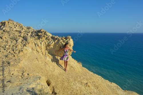 Girl Standing on Cliff Overlooking the Sea – Dramatic Coastal View