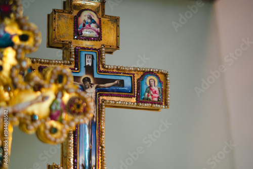 Antique crucifix of wood and gold filigran standing in front of a red velvet curtain