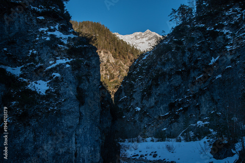 Dramatic entrance to the Stoißengraben gorge near Saalfelden, Austria, with sunlit snowy peaks in the background during late winter