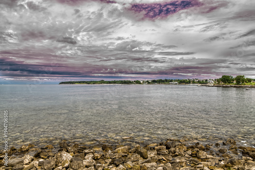 Rocky shoreline and clear sea water of the Istrian coast in Croatia under a dramatic cloudy sky.