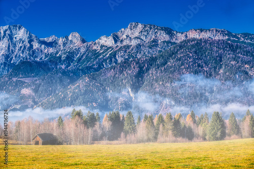 atmospheric autumn landscape with rising mist clearing over a mountain valley in saalfelden leogang featuring dramatic peaks