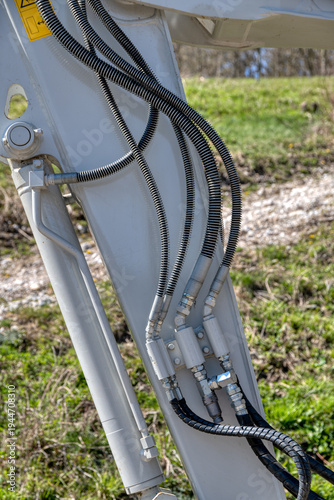 hydraulic hoses and lines on excavator arm close up, industrial machinery detail of hydraulic system with pressure pipes and connections in outdoor construction site