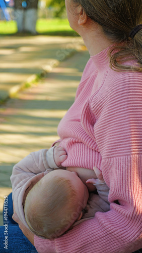 A mother nurtures her infant, breastfeeding in a quiet park. Close-up on the intimate bond, with soft sunlight filtering through trees. Candid, tender moment of motherhood and natural feeding