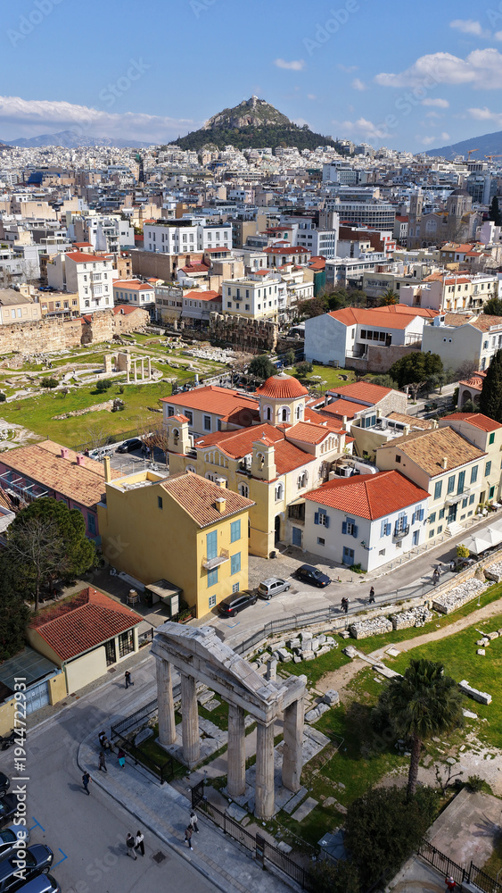 Fototapeta premium Aerial drone portrait photo of ancient Roman Market featuring tower of Winds and Gate of Athena in the heart of Athens historic centre built in Plaka district, below Acropolis hill, Attica, Greece