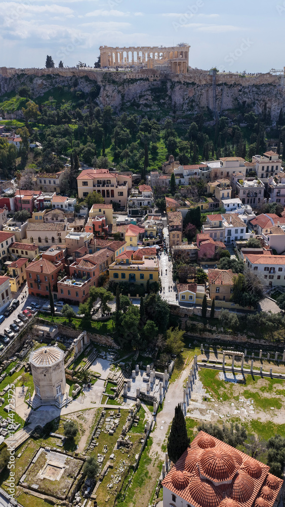 Fototapeta premium Aerial drone portrait photo of ancient Roman Market featuring tower of Winds and Gate of Athena in the heart of Athens historic centre built in Plaka district, below Acropolis hill, Attica, Greece