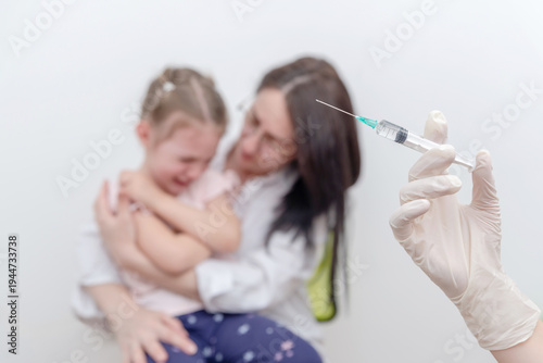 Crying child comforted by mother while medical worker holds syringe for vaccination, concept of pediatric immunization, childhood vaccines and healthcare prevention