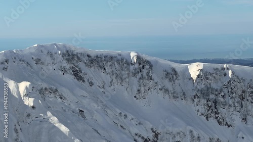 Snow covered mountain ridge and alpine peaks near Krasnaya Polyana at altitude 2200 meters with distant horizon and winter landscape panorama. Mountain tourism promotion, winter travel
