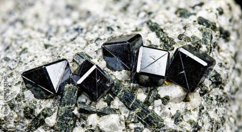 Black twinned loparite crystals with metallic luster within alkaline nepheline syenite.