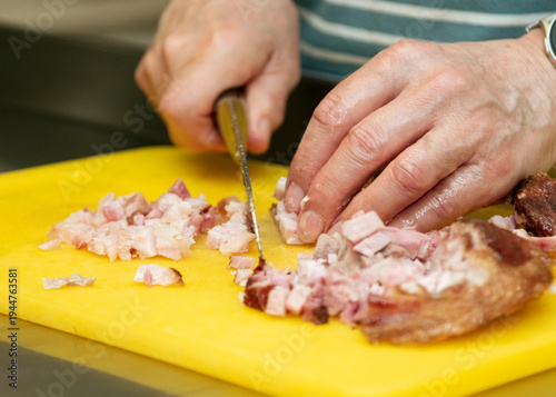 Bild auf Leinwand Hands of a person chopping diced meat on a yellow cutting board with a knife, sh