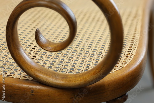 Curved wooden detail on a woven chair showcasing craftsmanship and design from a close perspective