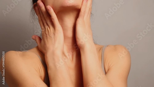 Beautiful woman doing stretching and massaging exercise the neck platysma muscle for healthy face skin, beauty and youth, freshness in studio lighting. Closeup healthy lifestyle video