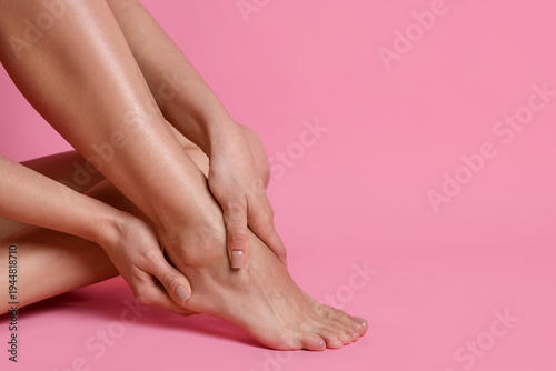 Photos Woman doing foot massage herself on pink background, closeup
