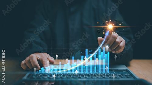 Business growth analytics concept. Rising data chart and upward arrow on laptop with hand pointing to successes point. Business analytics, investment growth, profit increase and financial strategy.