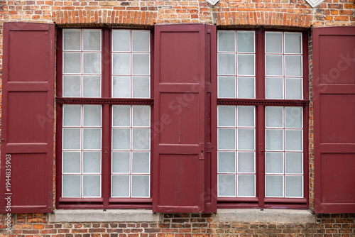 Bruges building facade displaying traditional red window shutters