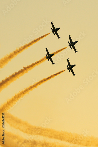 Four aerobatic planes in formation leaving curved smoke trails