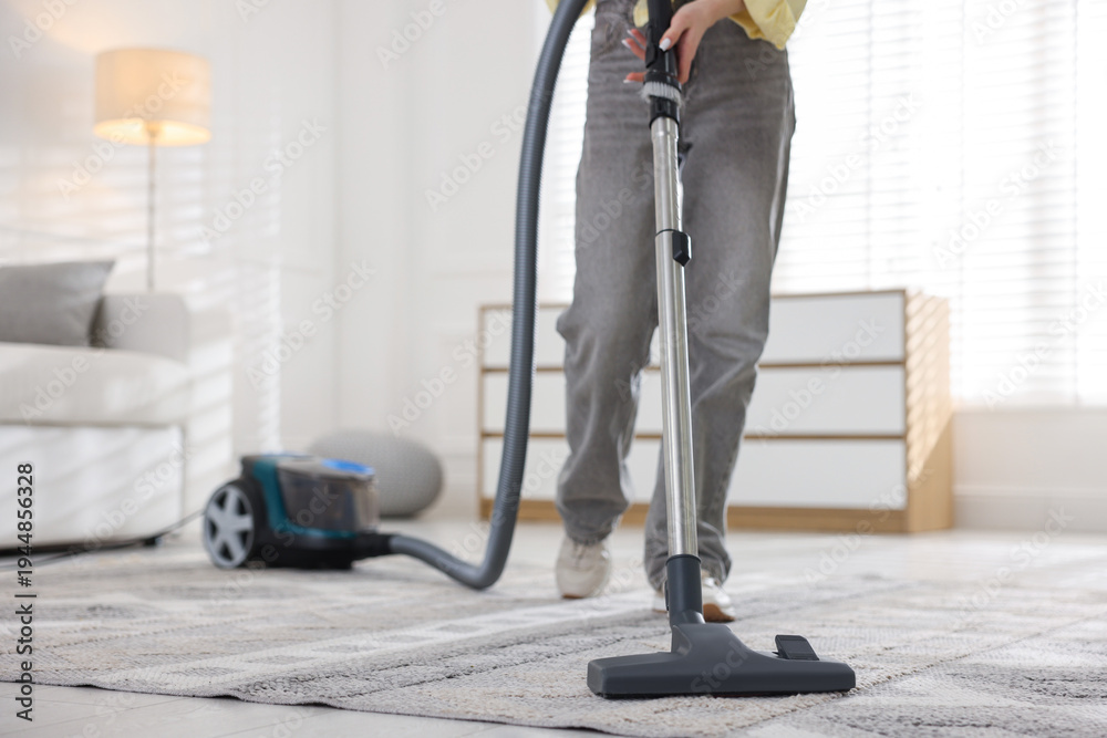 Fototapeta premium Teenage girl cleaning carpet with vacuum cleaner at home, closeup