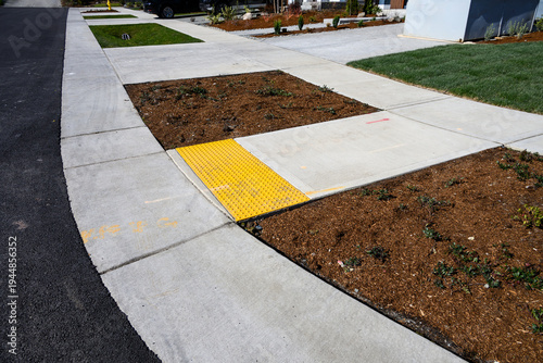 Obraz na plátně Freshly installed concrete sidewalk, yellow ADA Curb Ramp, and landscaping in ne