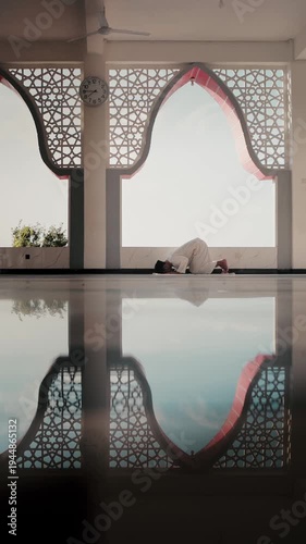 A Muslim man performing Islamic pray inside a mosque during Ramadan, a peaceful spiritual moment with beautiful mosque architecture and reflection on the polished floor.