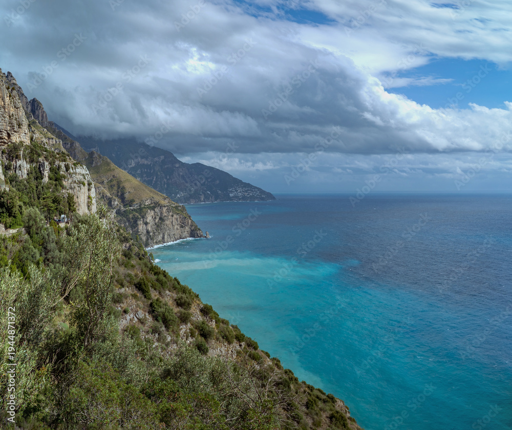 Fototapeta premium Amalfi Coast, Italy: Coastal cliffs and turquoise sea under cloudy sky