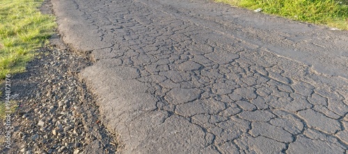 Macro photography of severely cracked and damaged asphalt road surface. Detailed texture showing material failure for construction and repair concepts.