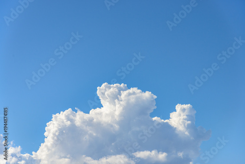 Cumulus white clouds bodies towering in clear blue sky background.