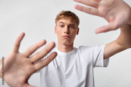 Tableau sur toile Hands reach toward the camera around a youth in a white t shirt, studio setting,