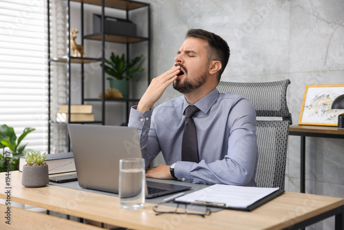 Man feeling fatigue at wooden desk in office