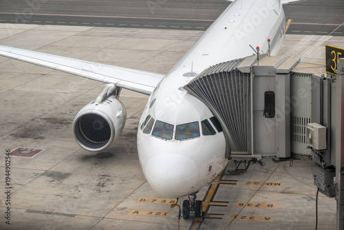 Konstfotografi Front view of passenger aircraft parked at terminal gate with jet bridge attache