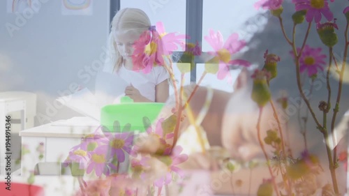 Seated kid focusing on worksheet, writing classwork; standing kid moving green bin, pink overlaying