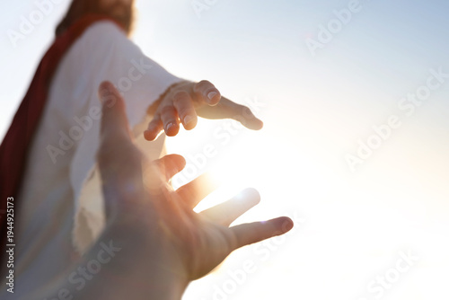 Photos A desperate Christian hand reaching out to the hand of Jesus Christ, with a bright sunny background, concept of faith and salvation