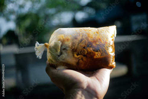 close up of hand holding take away Indonesia street food called batagor in transparent plastic package