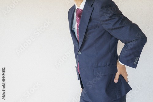 スーツを着た腰痛の男性　イメージ